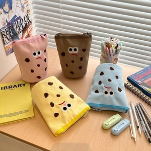 Detailed view of four colorful embroidered canvas pencil cases on a wooden desk