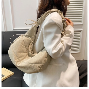 Detail of beige quilted cloud bag with ruched shoulder strap on a white blazer outfit