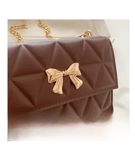 Close-up of dark brown quilted leather bag with a gold bow buckle and chain strap