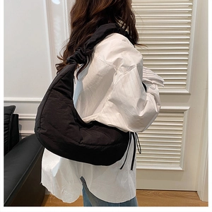 Detailed view of black quilted dumpling bag texture and pleated shoulder strap design