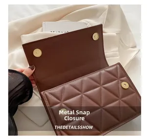 Close-up of golden magnetic snap closure and quilted leather texture on brown handbag
