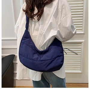 Detail view of the deep blue quilted hobo bag with moon-shaped design and wide strap