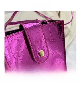 Close-up of rose pink metallic crocodile texture bag with golden round snap button