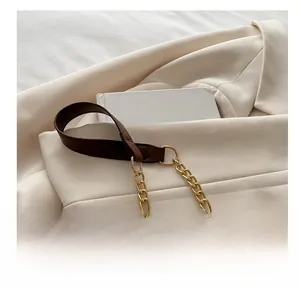 Detail of dark brown leather strap connected to elegant gold metal chain on chic bag