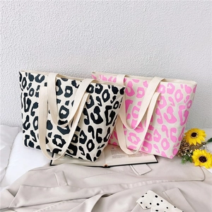 Detailed view of large pink leopard print canvas tote bag on cozy home bedding decor