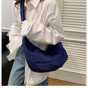 Detail of a dark blue quilted cloud bag with puffy texture and wide shoulder strap style