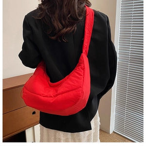 Fashionable red quilted dumpling bag worn as a shoulder bag on a female model