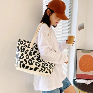 Detail of a large canvas tote bag with black and white leopard print on a female model