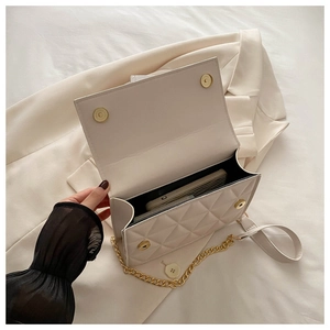 Detailed macro view of white quilted chain bag showing interior capacity and magnetic closure