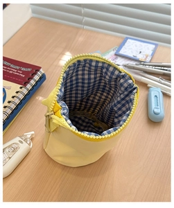 Detailed macro view of yellow canvas pencil case with blue checkered lining and zip closure