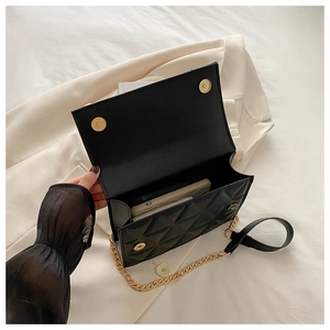 Detailed internal view of black quilted crossbody bag showing storage capacity for phone