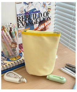 Detail of a bright yellow canvas standing pencil case with zipper and textured fabric finish