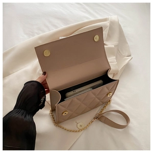 Detailed interior of a beige quilted crossbody bag showing storage space for smartphones