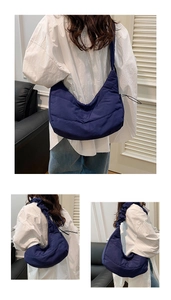 Macro view of navy blue quilted moon bag showing nylon texture and pleated strap detail