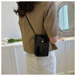 Detail of glossy black faux crocodile skin pattern on rectangular crossbody mobile phone bag