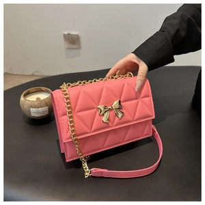 Detailed view of pink quilted handbag featuring a gold metal bow and chain strap