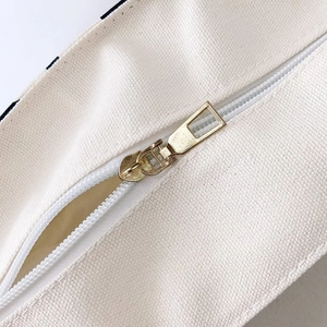 Detail of the high-quality white resin zipper with a gold metal puller on canvas bag