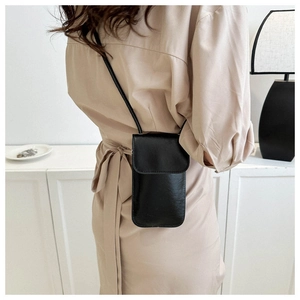 Détail d'un petit sac à bandoulière noir carré porté par un mannequin en extérieur