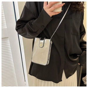 Detailed view of silver crocodile texture and gold clasp on vertical crossbody phone bag
