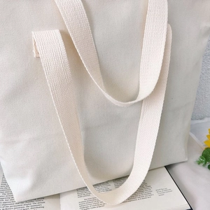 Close-up of off-white canvas tote bag showing thick woven texture and handle detail
