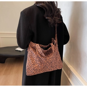 Detail shot of a large leopard print tote bag featuring canvas material and long straps
