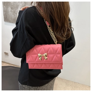 Detailed shot of pink quilted crossbody bag with gold bow clasp and metal chain