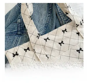 Detail of off-white corduroy tote bag showing black bow print and quilted rhombus stitching