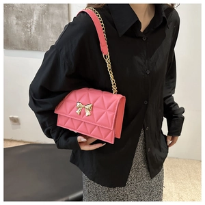 Detailed close-up of pink quilted crossbody bag with a golden bow and chain strap