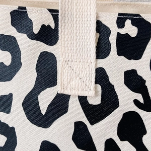 Detail of cross-stitched cream canvas handle on a leopard print tote bag for durability