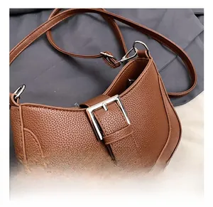 Close-up of brown litchi pattern leather shoulder bag with silver metal buckle detail