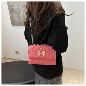 Detailed side view of pink quilted handbag with gold bow buckle and chain strap
