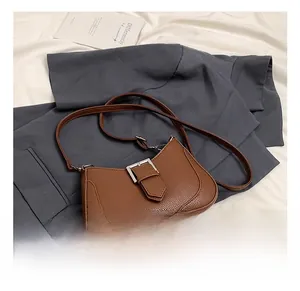 Detail of brown litchi pattern leather shoulder bag with vintage metal square buckle closure