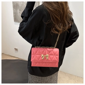 Detailed back view of model wearing a pink quilted crossbody bag with golden bow hardware