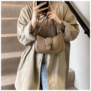 Close-up of brown pebbled leather crescent bag with adjustable silver buckle strap