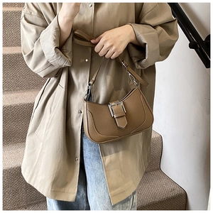 Detailed macro view of the brown lychee pattern leather shoulder bag with silver buckle