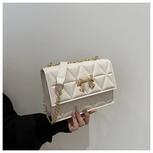 Detailed macro view of white quilted texture with gold bow clasp and elegant chain strap