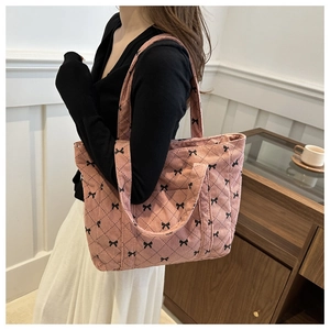 Close-up of pink corduroy tote bag with black bow patterns and quilted stitching details