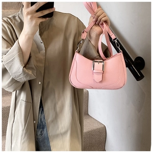 Detailed close-up of pink litchi grain leather crescent bag with silver buckle accent