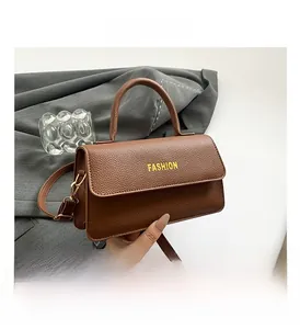 Close-up of brown litchi grain leather handbag featuring yellow FASHION text and gold buckles