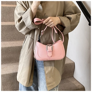 Detail of pink crescent bag with litchi texture and square silver buckle being held