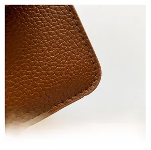 Detailed macro view of the brown litchi pattern leather and fine stitching on the handbag