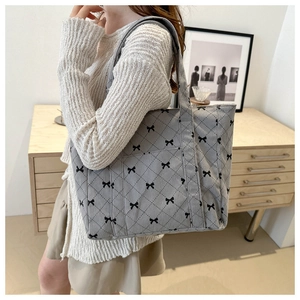 Close-up of gray corduroy tote bag with black bow patterns and quilted stitching details