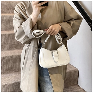 Detail of white crescent shoulder bag with pebbled leather texture and decorative strap