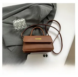 Detailed macro shot showing brown lychee grain leather texture and fashion lettering
