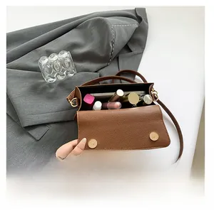 Internal view of brown litchi grain leather crossbody bag showing cosmetics storage space