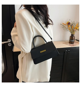 Model showing a black lychee texture leather handbag with gold lettering for daily style
