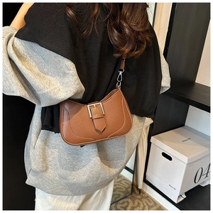 Detail view of the brown crescent bag featuring litchi grain faux leather and silver buckles