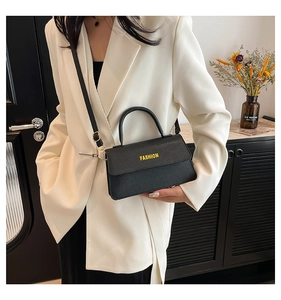 Close-up of black litchi texture handbag with yellow FASHION text and metal buckle