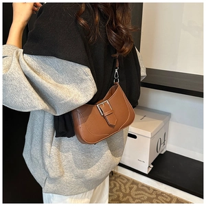 Detailed view of a brown pebbled leather crescent hobo bag with silver buckle and hardware