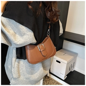Close-up of caramel leather crescent bag with litchi grain and silver buckle detail